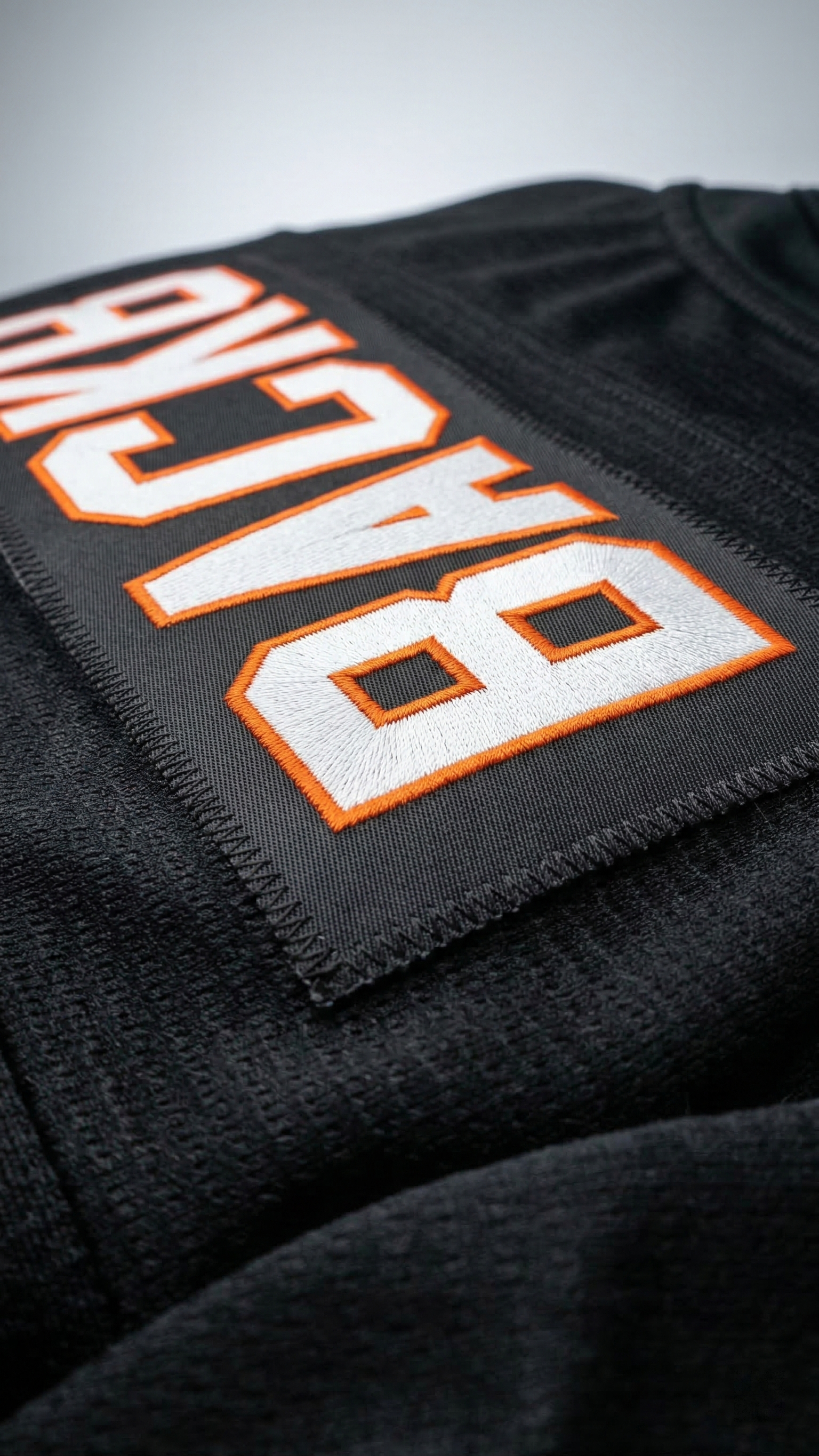 Black jacket with 'Backpack' text in orange and white on a gray background