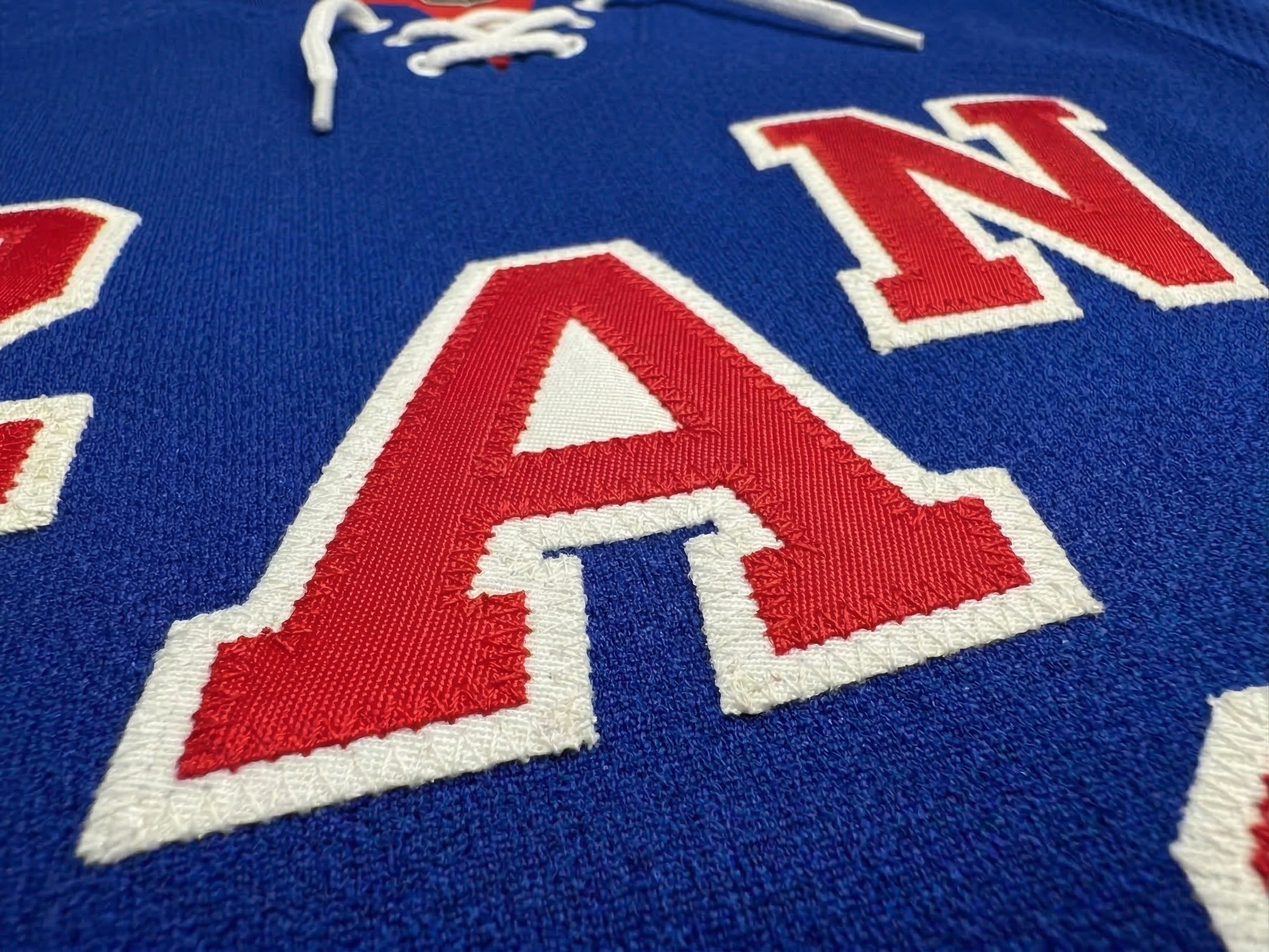 Close-up of a blue Kobe Sportswear jersey with a red and white embroidered patch