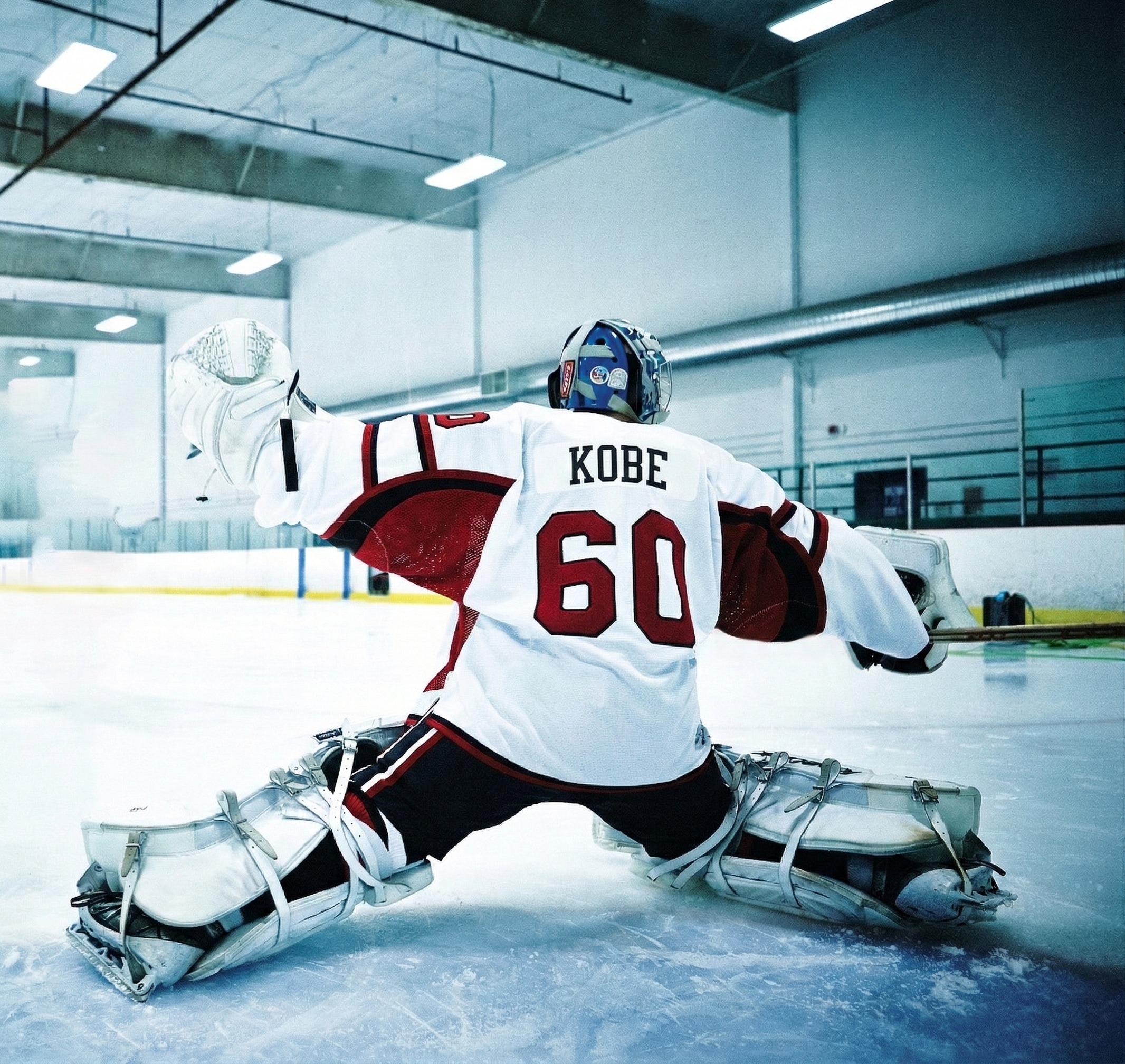 Kobe Sportswear Hockey player in a white jersey with red accents, number 60, on an ice rink.